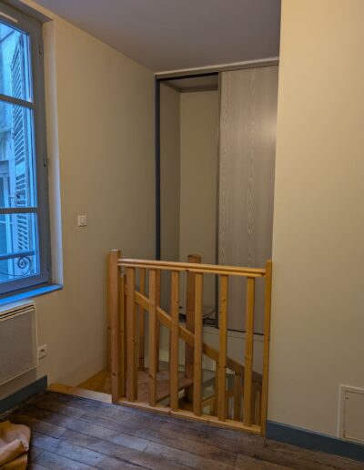 Arrivée escalier avec garde-corps en bois massif et placard coulissant existant, dans un espace sous-exploité à l’étage.