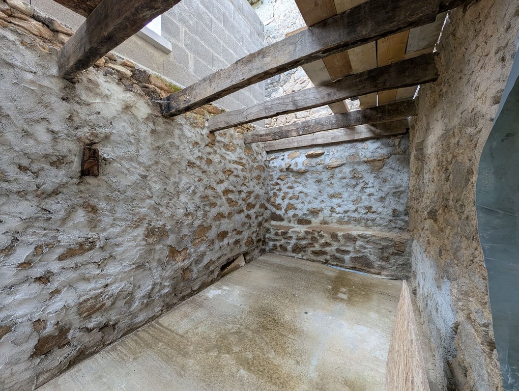 Petit volume annexe avec murs en pierre, plancher béton au sol et solivage pour surélévation