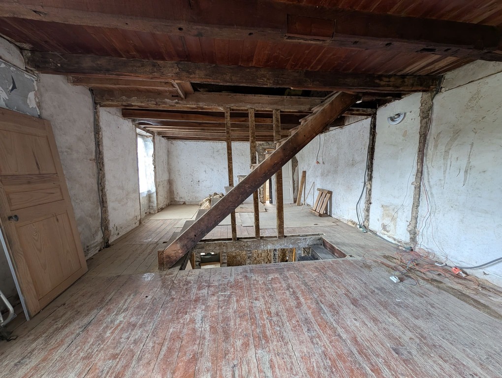 Vue de l’étage après démolition, plancher en bois ancien et poutres apparentes, trémie ouverte.