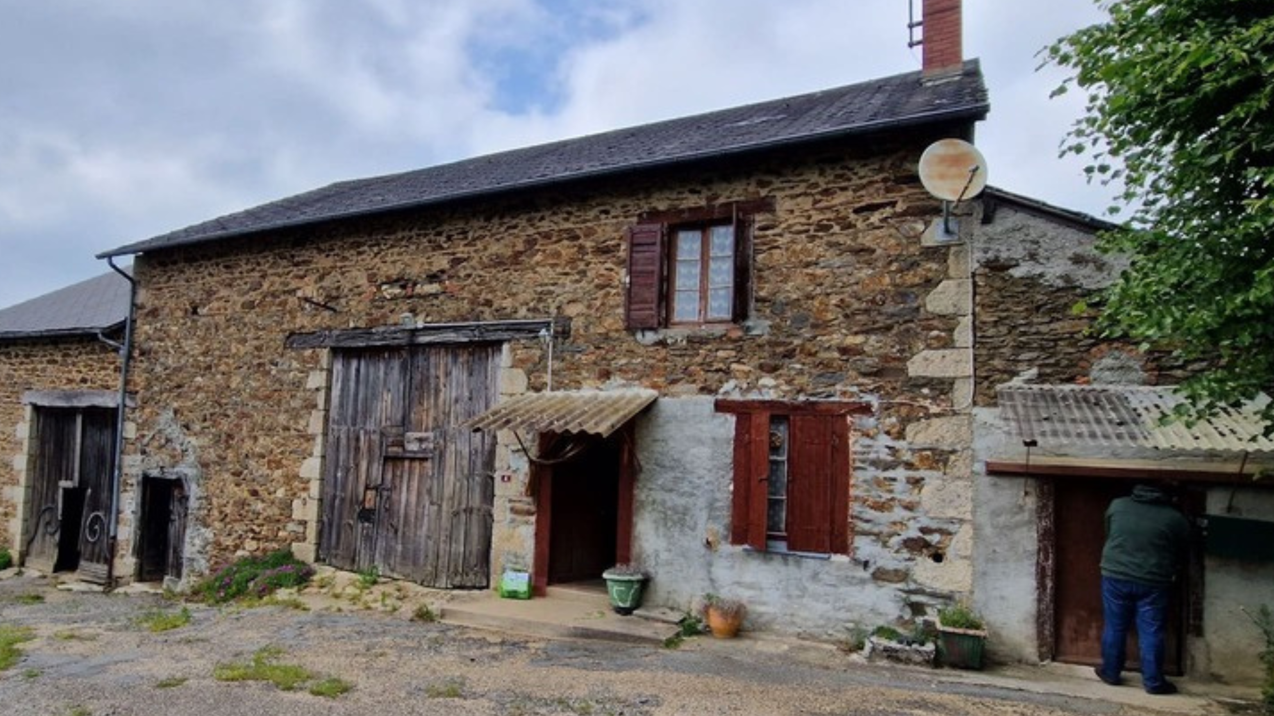Vue extérieure de la grange en pierre pendant le chantier, avec les ouvertures recréées, les nouvelles menuiseries posée et le rejointoiement révélant l’évolution du bâti agricole vers une habitation.