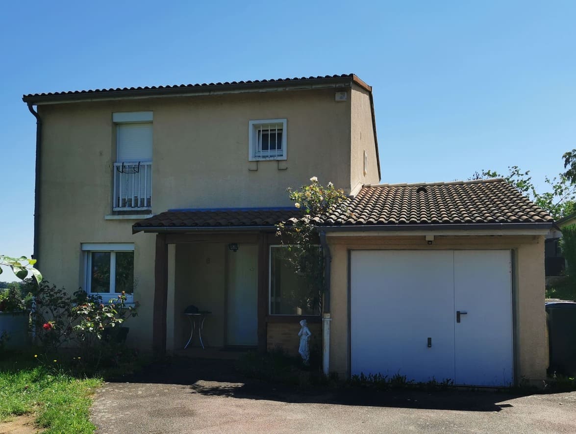 Façade principale rénovée avec nouvelle extension d’entrée en toiture plate, porte d’entrée gris anthracite et auvent métallique contrastant avec la toiture tuilée du garage accolé.
