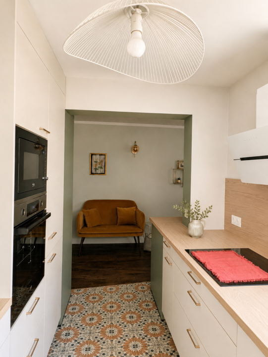 Vue depuis la cuisine rénovée vers le séjour à travers une ouverture soulignée en vert sauge